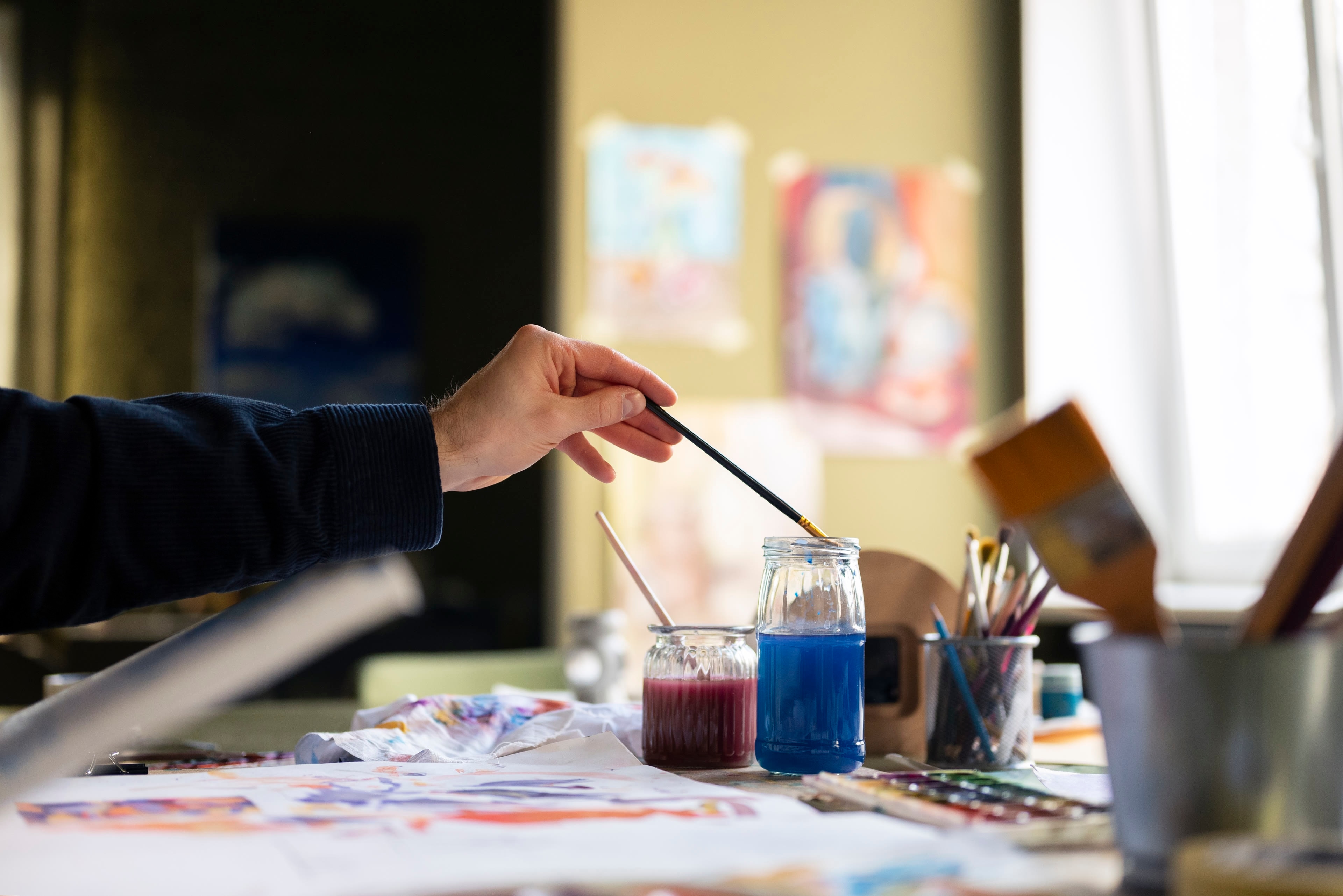 Várias pessoas a pintar em aguarela à volta de uma mesa do atelier